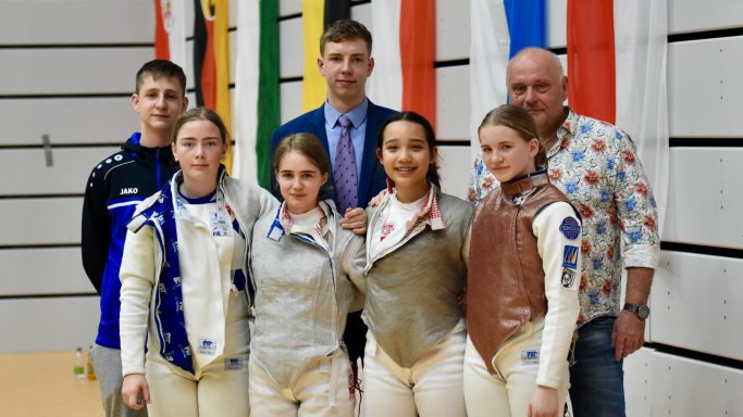 Gruppenfoto mit fünf Fechterinnen und drei Trainern in Sportkleidung.