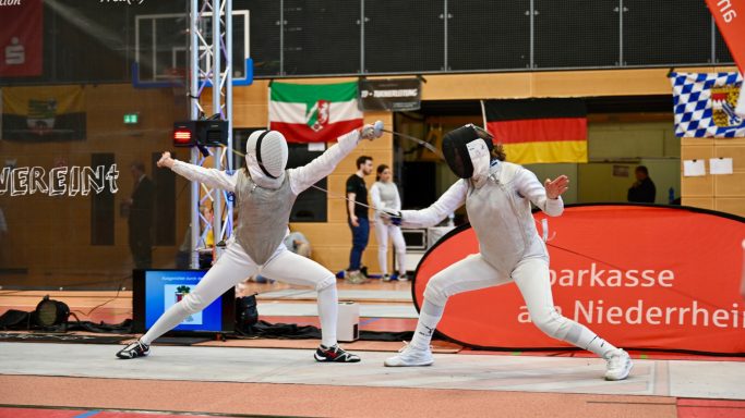 Zwei Fechter in Aktion, im Hintergrund Flaggen von Deutschland und anderen Ländern.